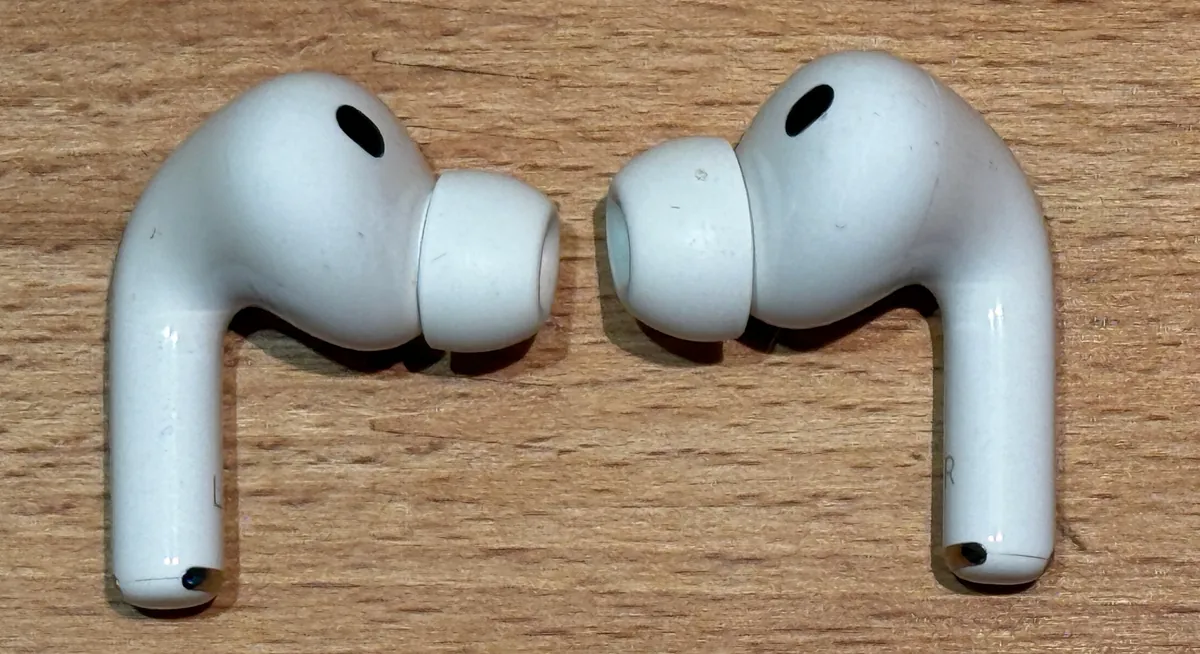 AirPods Pro 3 earbuds, left and right, side view on a wooden table