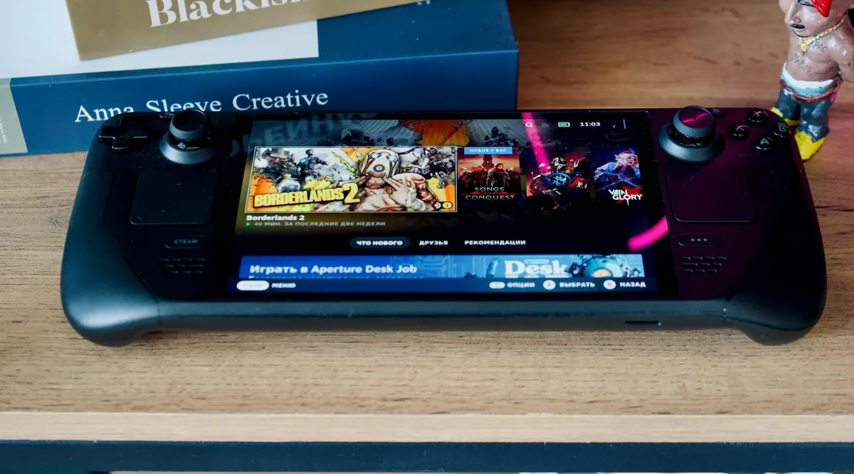 Steam Deck OLED, front view with the Steam library on screen, on a wooden shelf