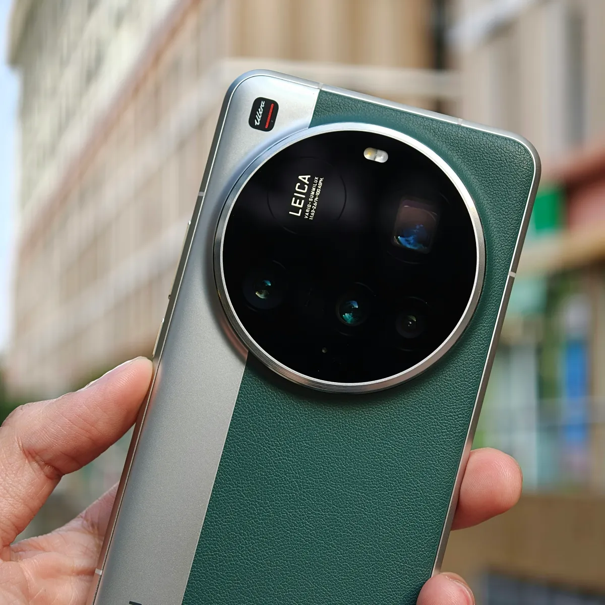 Xiaomi 15 Ultra in two-tone green and silver, back view showing the Leica camera module, held in hand
